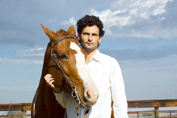 Adult man with horse outdoors on grass.