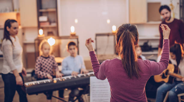 Teaching to play music in orchestra Group of kids teaching to play instruments in music school conservatory education building stock pictures, royalty-free photos & images