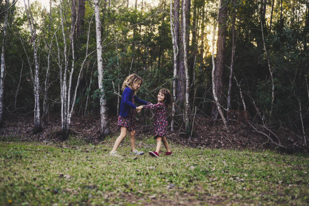Wood Nymphs Two little girls, age 4 and 7 in matching outfits, run, play, dance, and frolic with joy and happiness in a wooded area, forest. They are wearing matching outfits and full of freedom, happiness, and wild childhood abandon matching outfits for sisters stock pictures, royalty-free photos & images