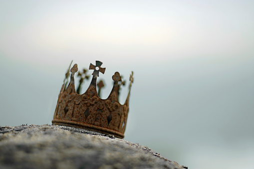 A small rusted crown in very shallow DOF against a dark out of focus sky and sea                                