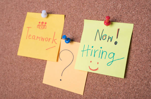 istock Now hiring text on sticky note or post is on cork bulletin billboard. 928702386