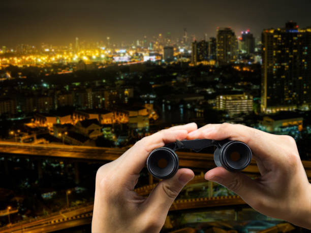 istock Binocular on hand holding and cityscape at night 928719312