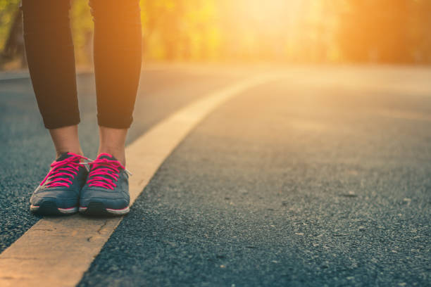 istock Women runner feet on road in workout wellness concept. 928722100