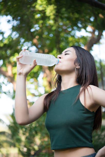 istock Young beautiful woman relaxing outdoors drinking water in the park. 928751916