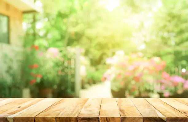 Photo of Empty wood table top on blur abstract green from garden and house background