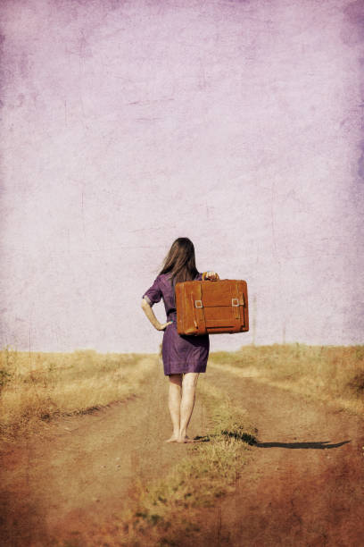 istock girl with suitcase walking on the road 928772188