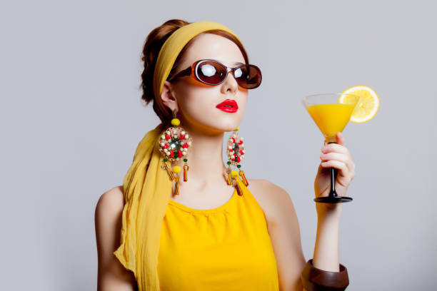 girl in 70s clothes style with tropical cocktail Young redhead girl in 70s clothes style with tropical cocktail on grey background pics for classic pin up poses stock pictures, royalty-free photos & images