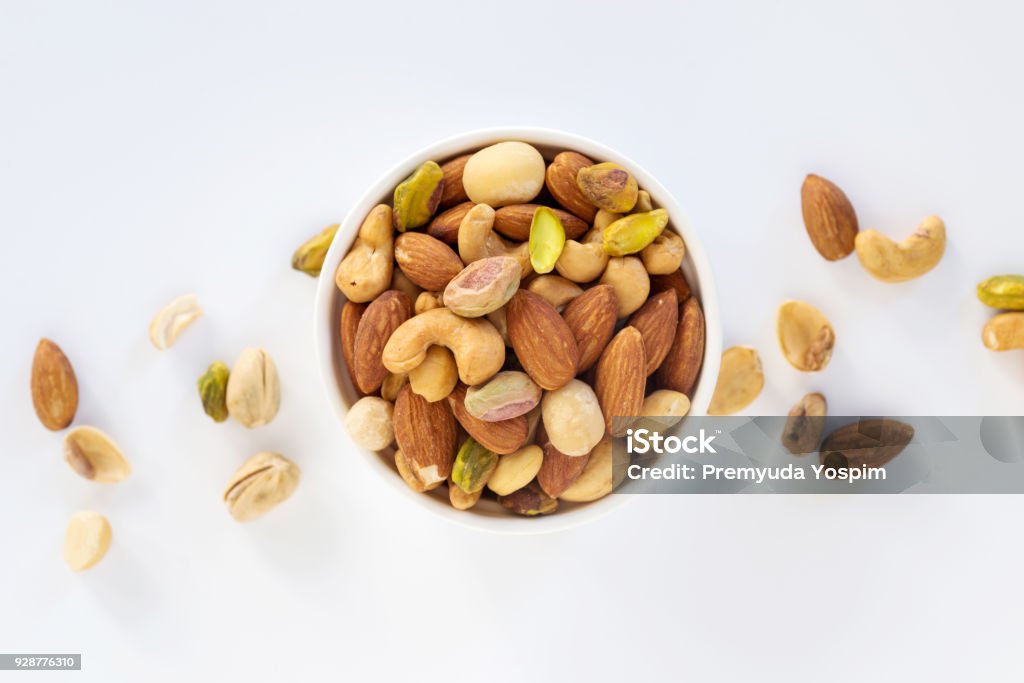 mixed nuts in bowl Healthy food and snack : mixed nuts in white ceramic bowl on white background from above, pistachios, almonds, hazelnuts and cashew Nut - Food Stock Photo