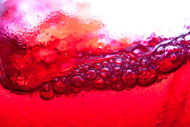 éclaboussures avec des bulles d’eau soda rouge fermer vers le haut et le point de rosée sur le verre - drink alcohol juice red photos et images de collection