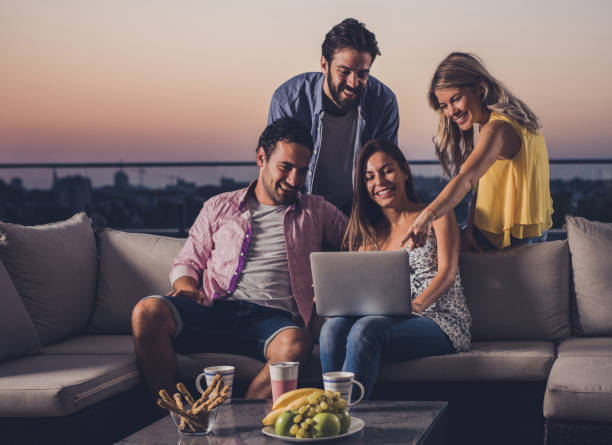istock Smiling couples using laptop together on a penthouse terrace. 928786526