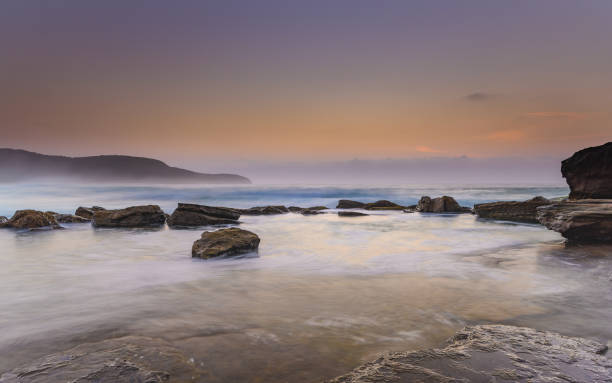 istock Hazy Sunrise Seascape with Rocks 928797826