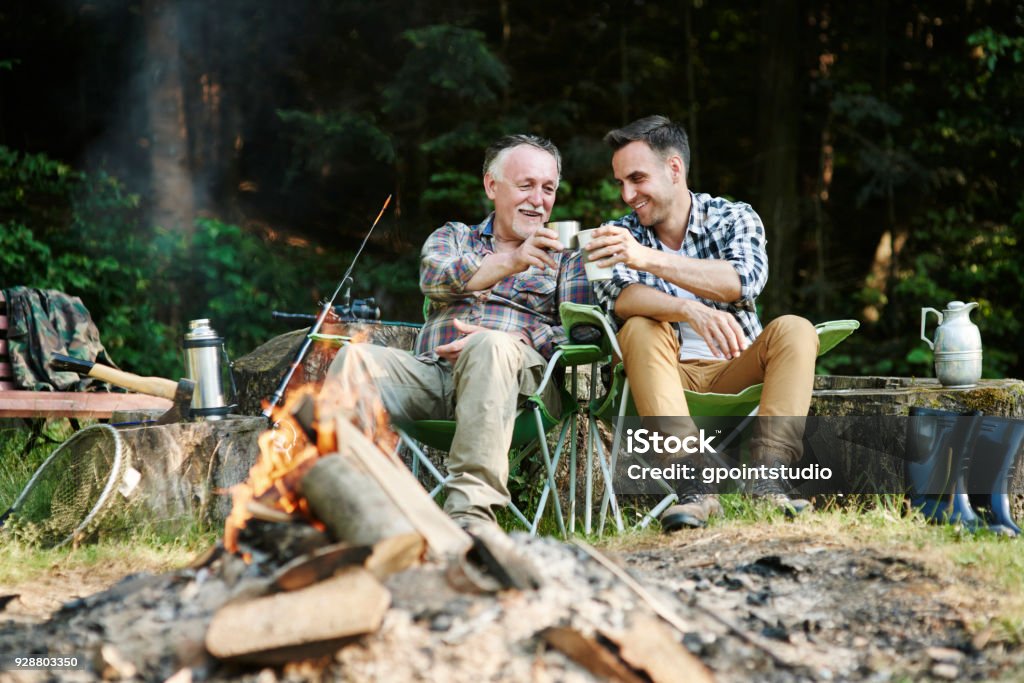 Fishermen drinking coffee beside bonfire Camping Stock Photo