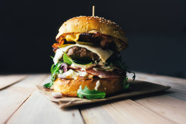 appetizing cheeseburger on wooden table. - bacon cheeseburger imagens e fotografias de stock