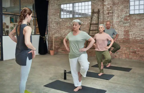 Photo of Female coach teaching yoga to seniors at gym
