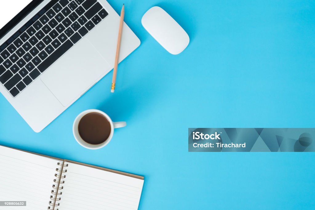 Minimal work space - Creative flat lay photo of workspace desk. Top view office desk with laptop, notebooks and coffee cup on blue color background. Top view with copy space, flat lay photography. Desk Stock Photo