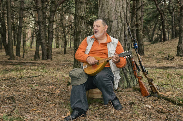 istock Singing senior hunter resting in evening forest and playing mandolin 928820124