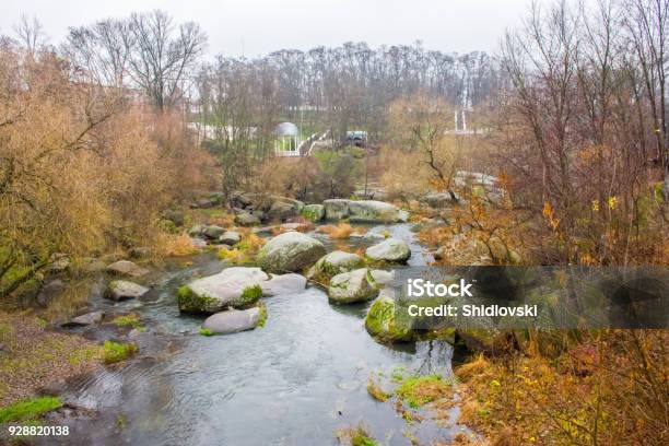 View From The Bridge On A Small River That Flows Through The Boulders And The Granite Stone Canyon In The Background On The Hillside Park With Pavilions And Stairways Autumn And Rainy Weather Stock Photo - Download Image Now