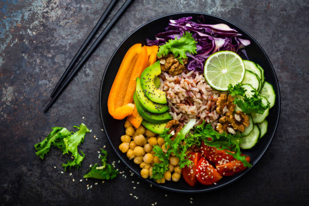 istock Buddha bowl dish with brown rice, avocado, pepper, tomato, cucumber, red cabbage, chickpea, fresh lettuce salad and walnuts. Healthy vegetarian eating, super food. Top view 928820158