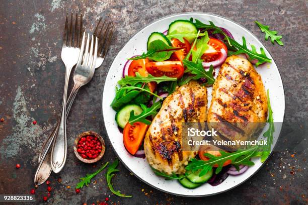 Grilled Chicken Breast Fried Chicken Fillet And Fresh Vegetable Salad Of Tomatoes Cucumbers And Arugula Leaves Chicken Meat With Salad Healthy Food Flat Lay Top View Dark Background Stock Photo - Download Image Now