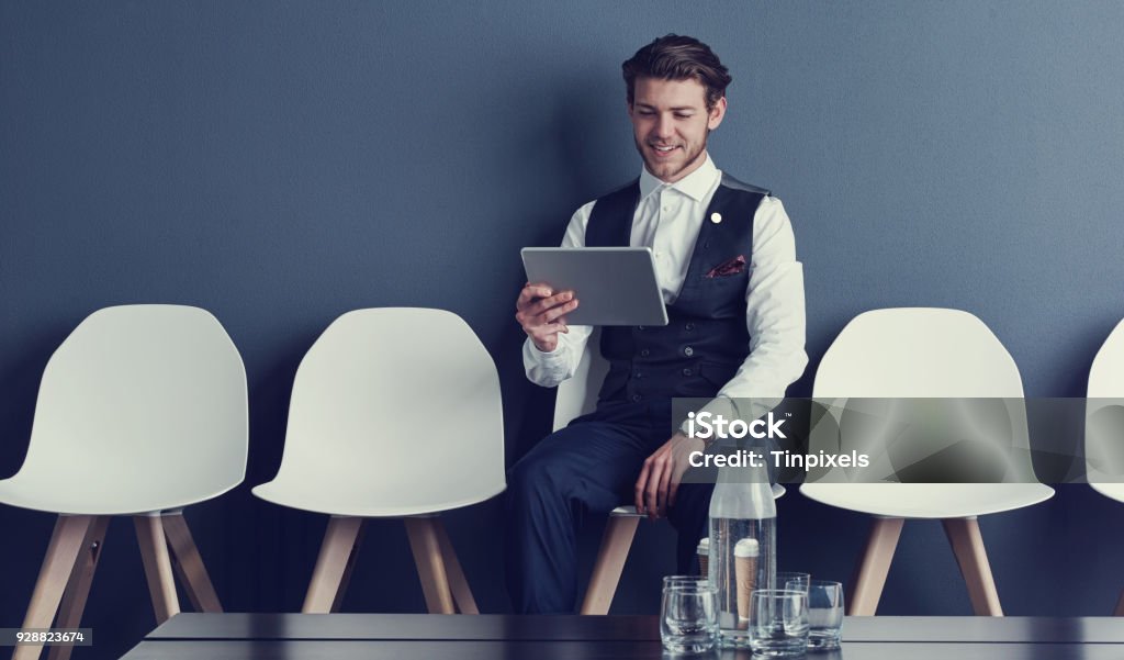 Looking up tips online to ace the interview Shot of a young businessman using a tablet while waiting for an interview 20-29 Years Stock Photo