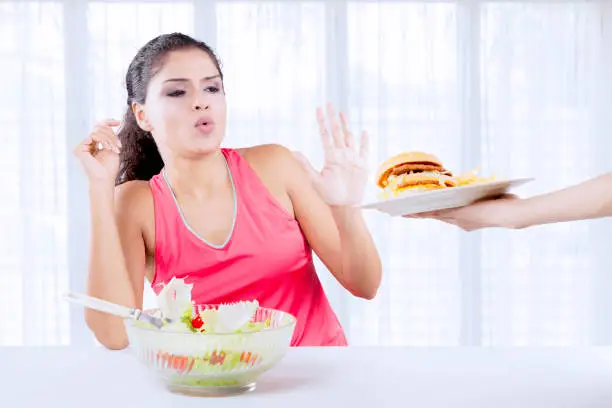 Indian woman refusing hamburger and chooses a bowl of Salad