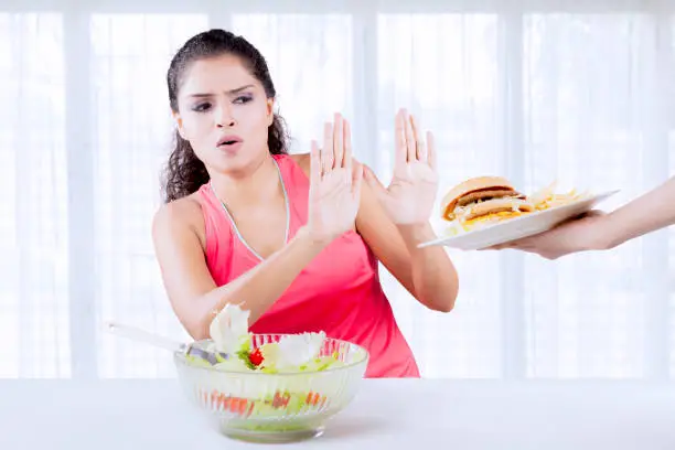 Indian woman refusing junk food and prefer a bowl of vegetable salad