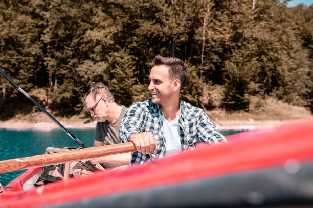 istock Two men sitting in rowboat and catching fish 928826532