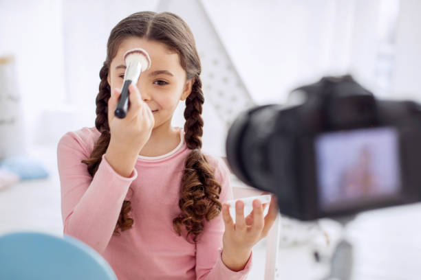 istock Charming girl applying powder to forehead while filming vlog 928827036