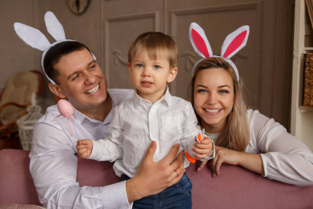 joyeuses pâques. jeune joyeuse famille avec enfant célébrant le jour de pâques. mère et père portant des oreilles de lapin de pâques dimanche - easter rabbit bizarre women photos et images de collection