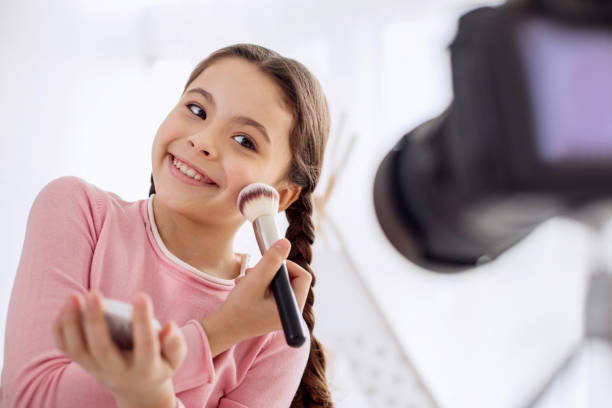 istock Cute girl posing while applying powder to cheeks 928832140