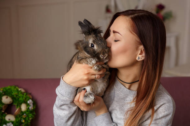istock Happy woman kissing Easter bunny with love on spring wreath with Easter eggs background 928832248