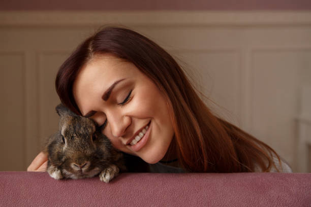 joyeuses pâques. jeune fille embrassant avec amour de lapin de pâques le jour de pâques. belle femme, la fête de pâques avec animaux domestiques - easter rabbit bizarre women photos et images de collection