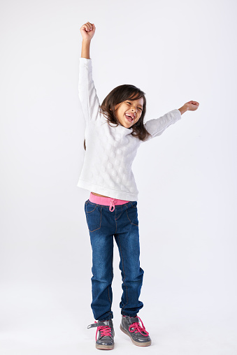 young girl celebrating with arms up and jumping isolated on white background