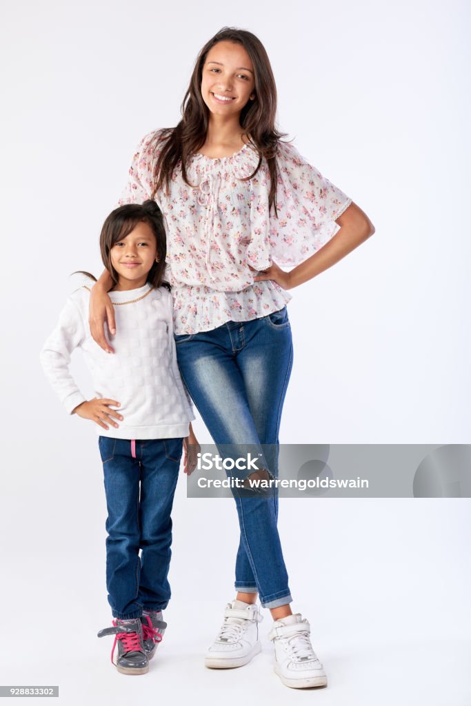 Portrait of two mixed race sisters smiling in studio portrait of two adorable mixed race sisters isolated on white in studio Sister Stock Photo