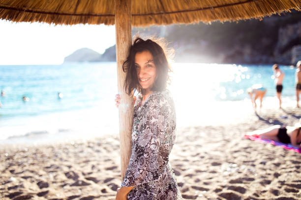 istock Smiling Young Woman Under Beach Parasol 928836752