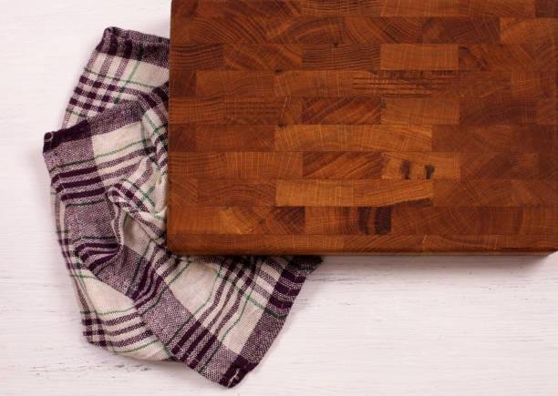 istock Old wooden cutting board with kitchen towel on white wooden table. 928844010