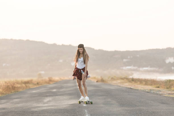 istock Beautiful girl with longboard skating on road 928844558