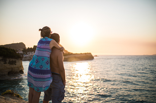 Couple Embracing Each Other On Pier And Looking At Sunset On Sea Horizon
