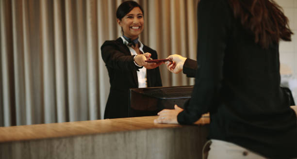 Concierge returning the documents to hotel guest Smiling female concierge returning the documents to hotel guest after check-in process. Female client receiving her documents at hotel reception desk after check-in. airport check in counter photos stock pictures, royalty-free photos & images