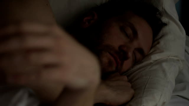 Calm bearded man sleeping in bed, breathing with open mouth, healthy sleep
