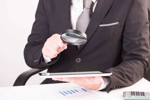 istock Businessman checking a tablet with magnifying glass 928854890
