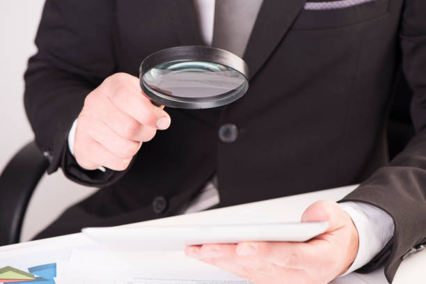 istock Businessman checking a tablet with magnifying glass 928855006