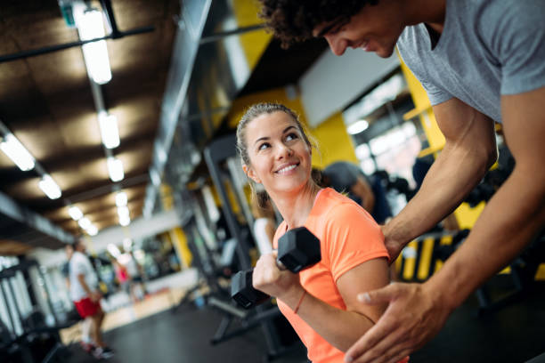 istock Young beautiful woman doing exercises with personal trainer 928855146