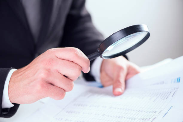 istock Businessman checking a tablet with magnifying glass 928855244