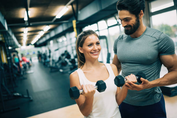 istock Young beautiful woman doing exercises with personal trainer 928855318