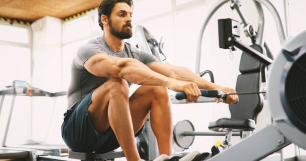 istock Fit man training on row machine in gym 928855720