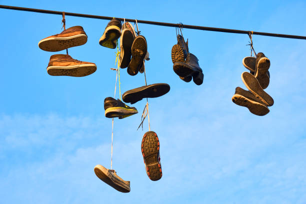 The dangling sneakers create a striking silhouette against the gray backdrop of an overcast day