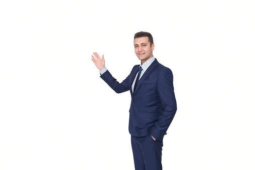 Portrait of smiling young businessman presenting against white background. Horizontal composition. Image taken with Nikon D800 and developed from Raw format. Studio shot.
