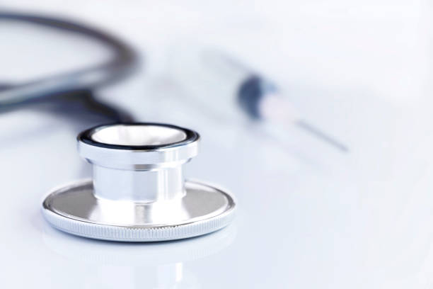 istock Stethoscope with a syringe on white table background. The stethoscope is a medical instrument for listening to the action of someone's heart or breathing. 928864134