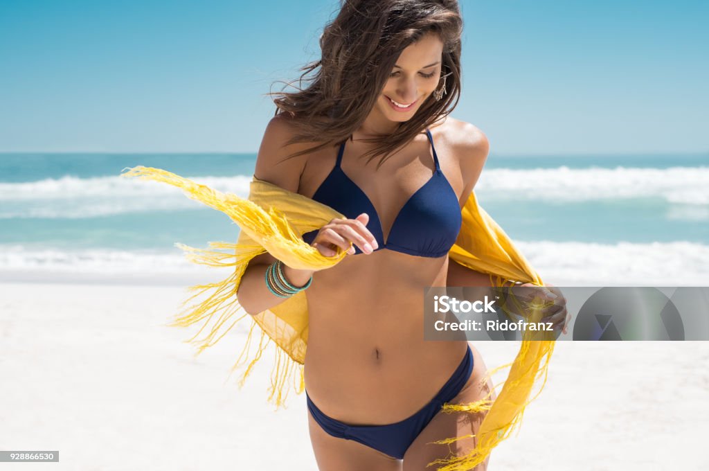 Beautiful woman running on beach Beautiful young woman running on the beach with a yellow tissue. Happy smiling girl with scarf enjoying at beach. Freedom and carefree concept. Women Stock Photo